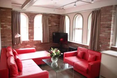 a living room with red couches and a tv at Base Serviced Apartments - Sir Thomas Street in Liverpool