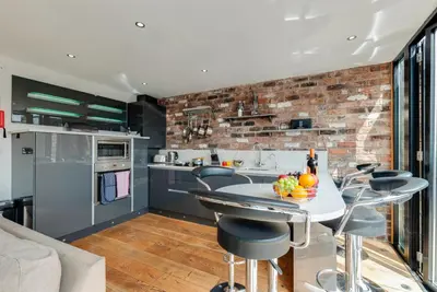 a kitchen with a brick wall and a table and chairs at Base Serviced Apartments - Sir Thomas Street in Liverpool