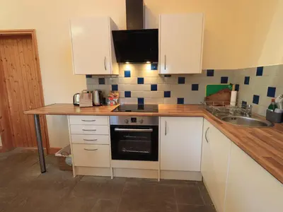 a small kitchen with white cabinets and a sink at Swallow cottage, Over Kellet in Over Kellet