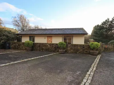 a house with a stone wall and a driveway at Swallow cottage, Over Kellet in Over Kellet