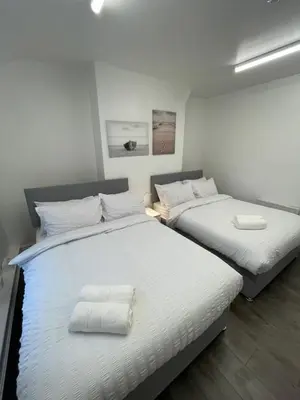two beds in a room with white walls and wood floors at County serviced accommodation in Liverpool
