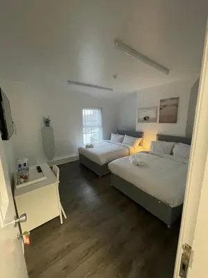 a bedroom with two beds and a table and a window at County serviced accommodation in Liverpool