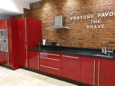 a kitchen with red cabinets and a brick wall at Infinity PartyPadsLiverpool Hen and Stag Welcome in Liverpool