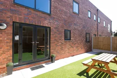 a wooden bench next to a brick building at Stunning 2 Bedroom Apartment in Wallasey in Wallasey