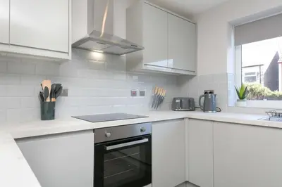 a kitchen with white cabinets and a stove top oven at Stunning 2 Bedroom Apartment in Wallasey in Wallasey