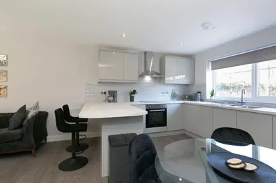 a kitchen with white cabinets and a table and chairs at Stunning 2 Bedroom Apartment in Wallasey in Wallasey