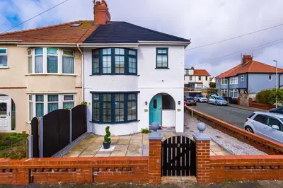 a white house with a blue door on a street at Families Only - Pet Friendly sleeps 6 maximum NO PARTIES in Blackpool