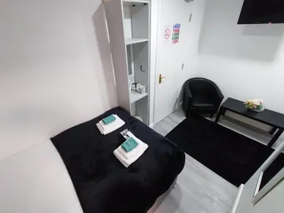 a small room with two beds and a chair at High Tide Hotel Oyo in Blackpool