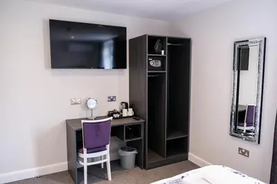 a bedroom with a desk with a purple chair and a mirror at Anelli Hotel in Southport