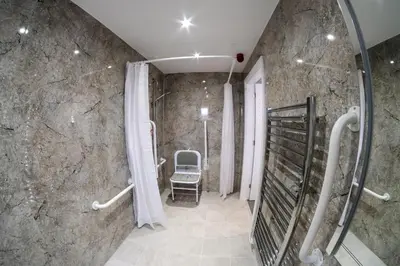 a bathroom with a shower with a chair in it at Anelli Hotel in Southport