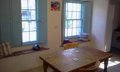 a dining room with a wooden table and two windows at Cottage - Sleeps 4 - Pets Ok - Garden - Parking in Carnforth