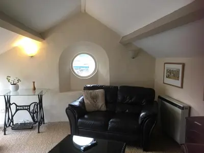 a living room with a black leather couch and a window at Cottage - Sleeps 4 - Pets Ok - Garden - Parking in Carnforth