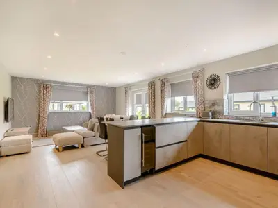 a kitchen with a counter top and a living room at Willows Cottage in Blackburn