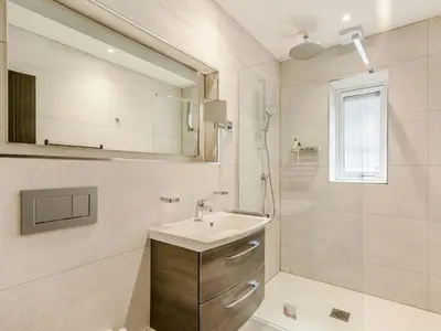 a white bathroom with a sink and a shower at Willows Cottage in Blackburn