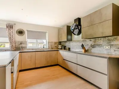 a kitchen with stainless steel appliances and wooden cabinets at Willows Cottage in Blackburn