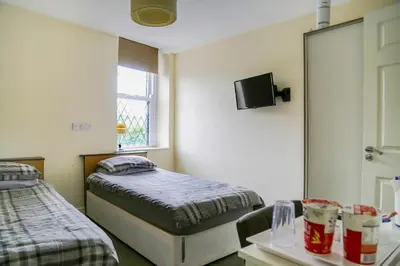 a room with two beds and a table and a mirror at OYO Castle Hotel, Accrington in Accrington