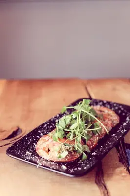 a black plate with a piece of food on a table at The Tavern at Hale in Milnthorpe