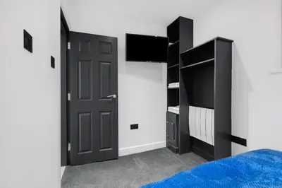 a bedroom with a black door and a tv at Winter Garden Apartments by Sasco in Blackpool