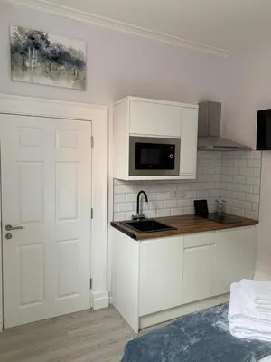 a kitchen with white cabinets and a sink and a door at Winckley Square Residences in Preston
