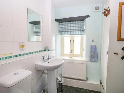 a white bathroom with a sink and a toilet at Tyee Cottage in Carnforth