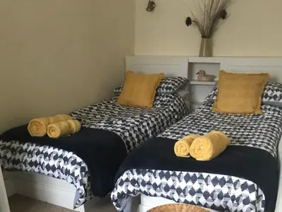 two beds in a room with black and white comforters at Tyee Cottage in Carnforth