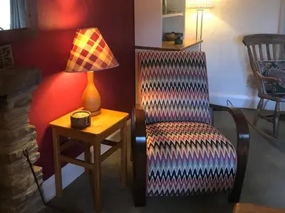 a room with a chair and a lamp and a table at Tyee Cottage in Carnforth