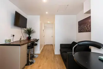 a living room with a black couch and a desk at Liverpool City Centre - Fabulous 3 En-suite Bedrooms - Sleeps 10 People in Liverpool
