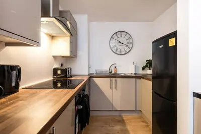 a kitchen with a black refrigerator and a clock on the wall at Liverpool City Centre - Fabulous 3 En-suite Bedrooms - Sleeps 10 People in Liverpool
