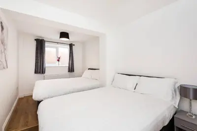 two beds in a white room with a window at Liverpool City Centre - Fabulous 3 En-suite Bedrooms - Sleeps 10 People in Liverpool