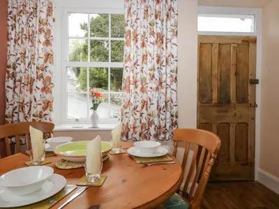 a dining room table with a window and a table and chairs at Mount Pleasant Cottage in Grange Over Sands