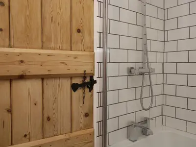 a bathroom with a wooden door and a shower at Mount Pleasant Cottage in Grange Over Sands