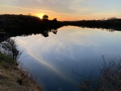 a reflection of the sky in a lake at sunset at KINGDOM HOLIDAY PARK in Haverigg