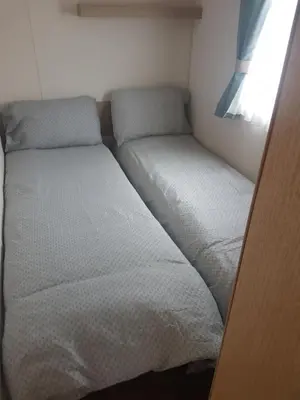 two beds in a small room with a window at KINGDOM HOLIDAY PARK in Haverigg