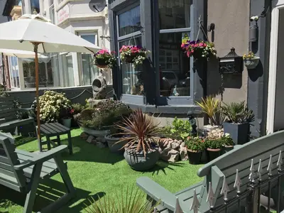 a patio with chairs and potted plants and an umbrella at The Glenroy Guest House in Blackpool