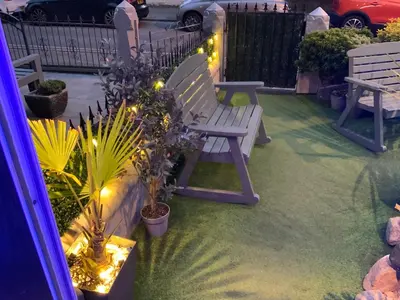 a patio with a bench and some plants and lights at The Glenroy Guest House in Blackpool