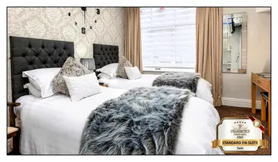two beds in a hotel room with white sheets at Pembroke Hotel in Blackpool