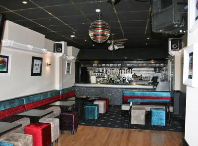 a restaurant with a bar with blue and red seats at The Blenheim Mount Hotel in Blackpool