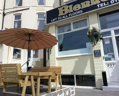 a wooden table with an umbrella in front of a store at The Blenheim Mount Hotel in Blackpool