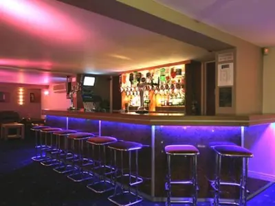 a bar with purple bar stools in a room at Dutchman Hotel in Blackpool