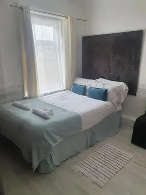 a bed with blue pillows in a bedroom with a window at Vista Sol in Blackpool