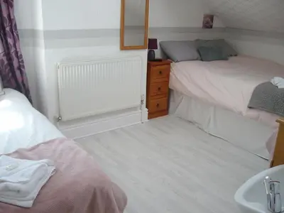 a bedroom with two beds and a sink and a mirror at Vista Sol in Blackpool