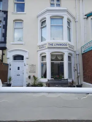 a white building with a bench in front of it at Lynwood Hotel in Blackpool