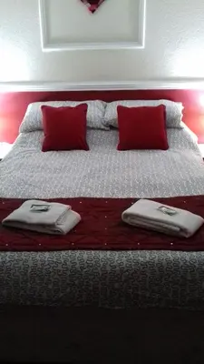 a bed with red pillows and towels on it at Lynwood Hotel in Blackpool