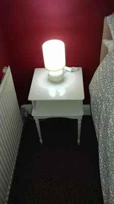 a table with a lamp on it next to a bed at Lynwood Hotel in Blackpool