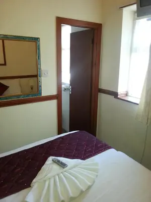 a room with a bed with a mirror and a remote control at Lynwood Hotel in Blackpool