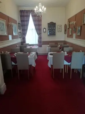 a dining room with tables and chairs and a chandelier at Shirley Heights Hotel in Blackpool