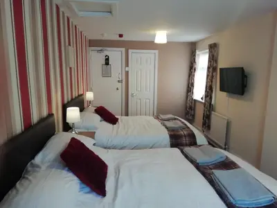 a bedroom with two beds and a television in it at Shirley Heights Hotel in Blackpool
