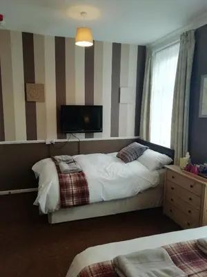 a bedroom with a bed and a tv on the wall at Shirley Heights Hotel in Blackpool