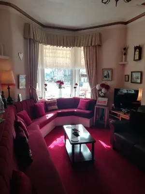 a living room with a red couch and a table at Shirley Heights Hotel in Blackpool