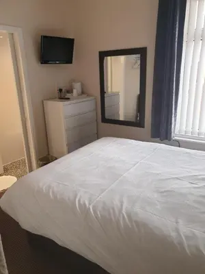 a bedroom with a white bed and a mirror at Langroyd Hotel in Blackpool
